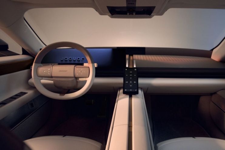 Futuristic interior of a Jaguar car, featuring a minimalist dashboard, white steering wheel, and a sleek central console d...