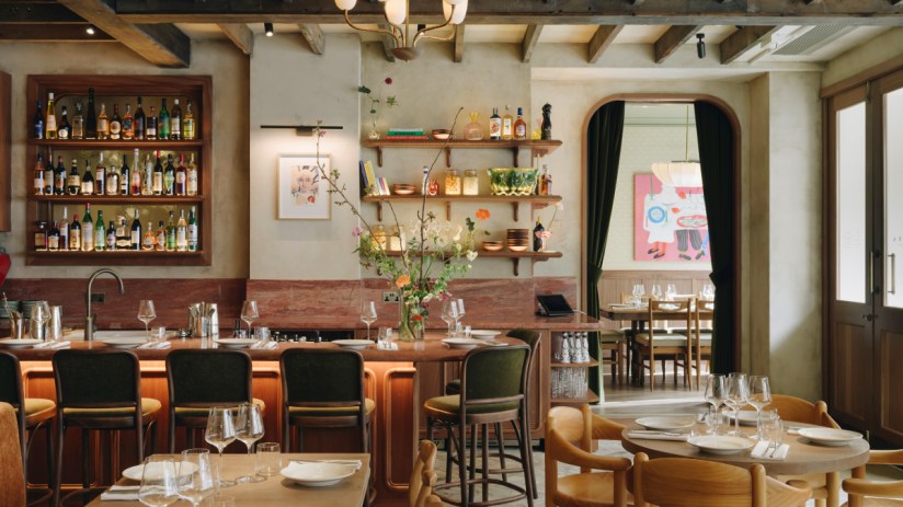 Lita restaurant interior with bar, bottles, shelves, and dining tables set with glasses and plates.
