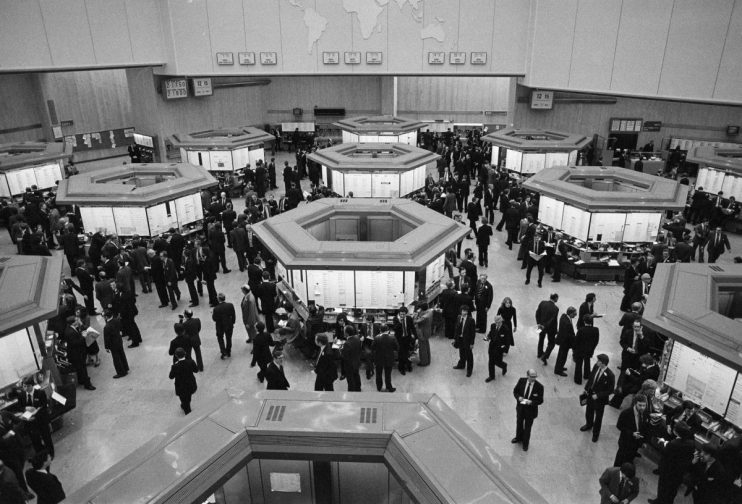 Busy London Stock Exchange trading floor in the 1980s with brokers at hexagonal trading posts.