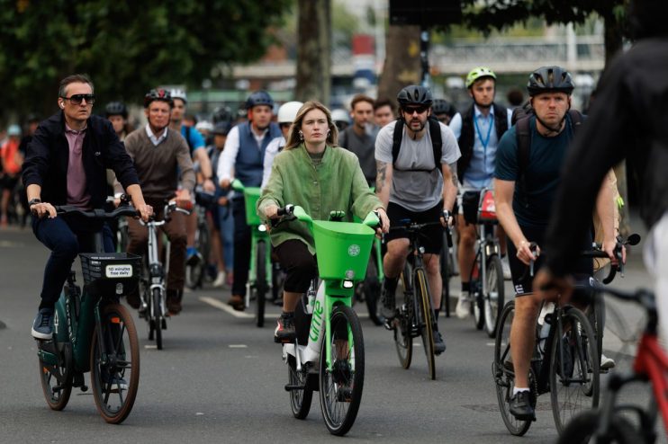 London cyclists ride Lime bikes and personal bicycles on a city street, promoting urban mobility and eco-friendly transport.