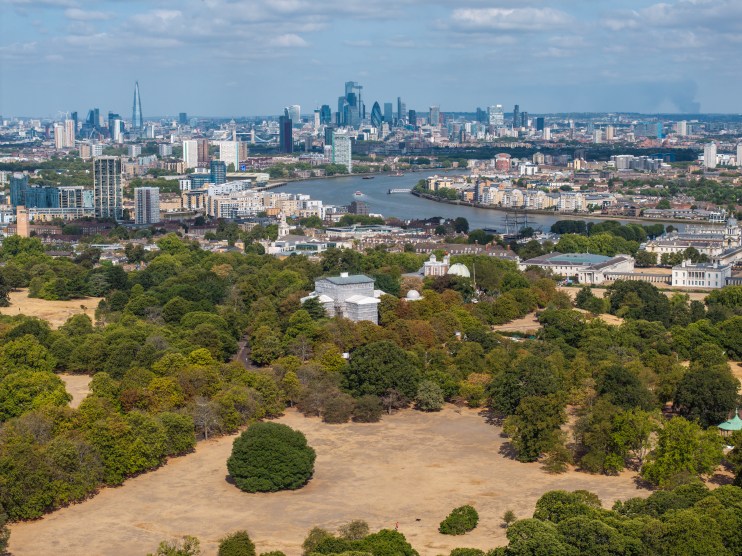 London cityscape from Primrose Hill showing dry, brown grass during drought with River Thames and skyscrapers