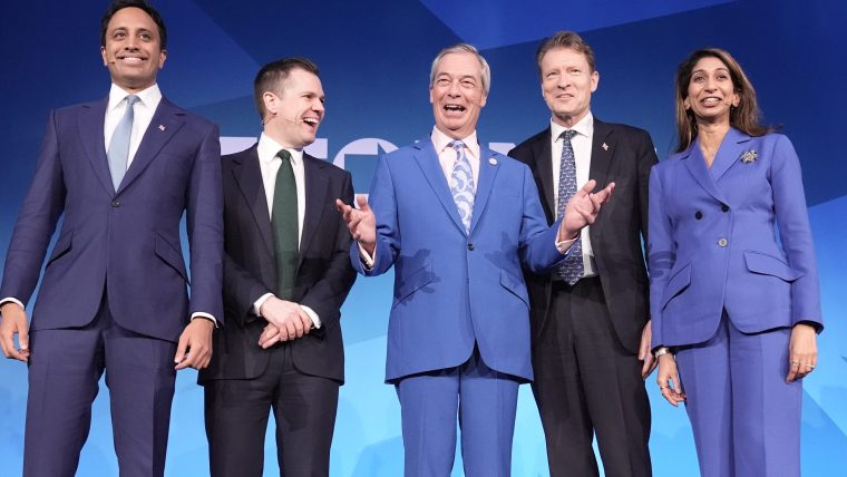 Reform UK leaders Nigel Farage, Richard Tice, and others smiling on stage against a blue background