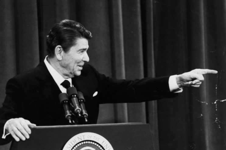Ronald Reagan at a podium in Washington in 1982, pointing to his right while speaking.