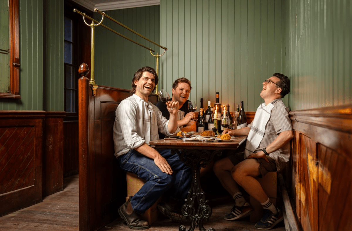 Three men enjoying wine and food, laughing in a cozy booth at Simpsons Tavern Cloth, Cornhill