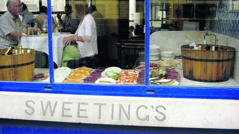 Sweetings Canada restaurant exterior, showing diners inside and a seafood display in the window.