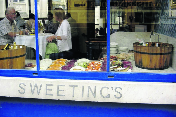 Sweetings Canada restaurant exterior, showing diners inside and a seafood display in the window.