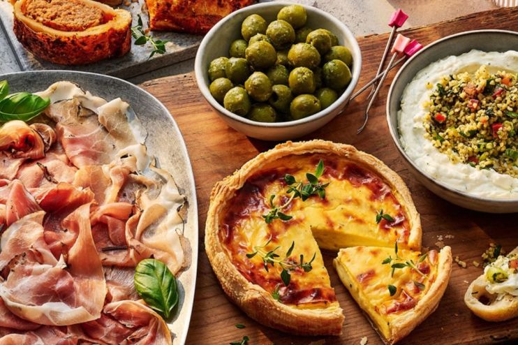 Tesco quiche, cured meats, olives, and dip on a wooden board, ready for a party or meal.