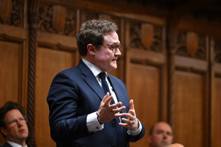 Tom Tugendhat, MP, speaks passionately, gesturing with hands in a formal setting with wood paneling.