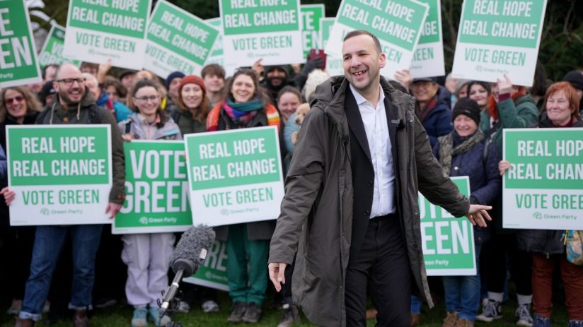 Zach Polanski at a Green Party rally with supporters holding Vote Green signs