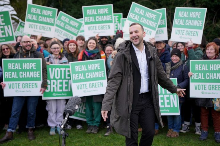 Zach Polanski at a Green Party rally with supporters holding Vote Green signs