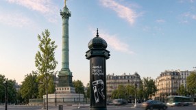 Revolut Banque Française ad on a Morris column in Paris, with the July Column and blurred traffic in the background.