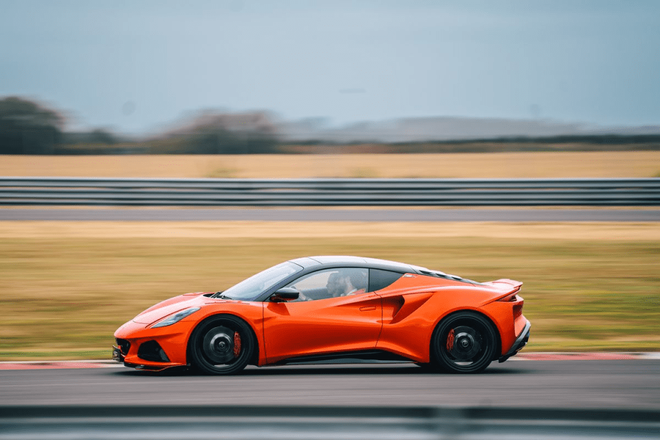 Orange sports car driving fast on a race track with a blurred background
