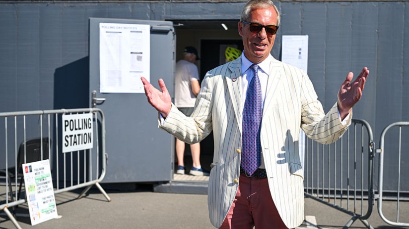 Nigel Farage, in a striped jacket and sunglasses, speaks outside a polling station.