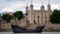 A replica historic sailing ship with a Spanish flag on the Thames River in front of the Tower of London