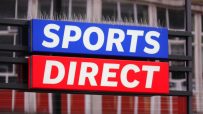 Sports Direct store sign with anti-pigeon spikes, showcasing the blue and red branding of the retail giant.