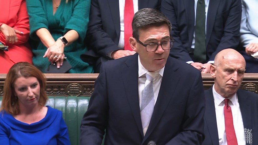 Andy Burnham speaking in Parliament, surrounded by other politicians and officials.
