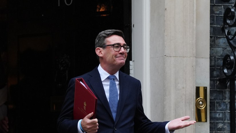 Andy Burnham, Mayor of Greater Manchester, in a dark suit holding a red folder outside 10 Downing Street