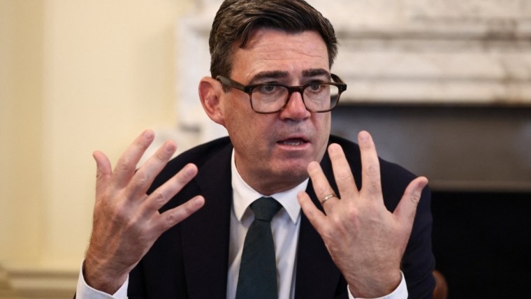 Andy Burnham, Mayor of Greater Manchester, speaking with hands gesturing, wearing a suit and glasses.