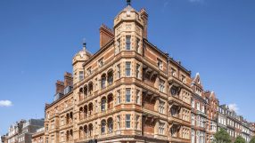 Ornate red brick and stone building at 1 Harley Street in London, with pedestrians crossing the street on a sunny day.