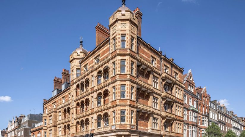 Ornate red brick and stone building at 1 Harley Street in London, with pedestrians crossing the street on a sunny day.