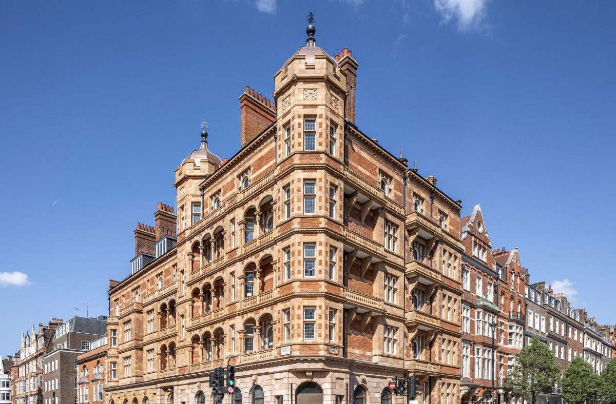 Ornate red brick and stone building at 1 Harley Street in London, with pedestrians crossing the street on a sunny day.