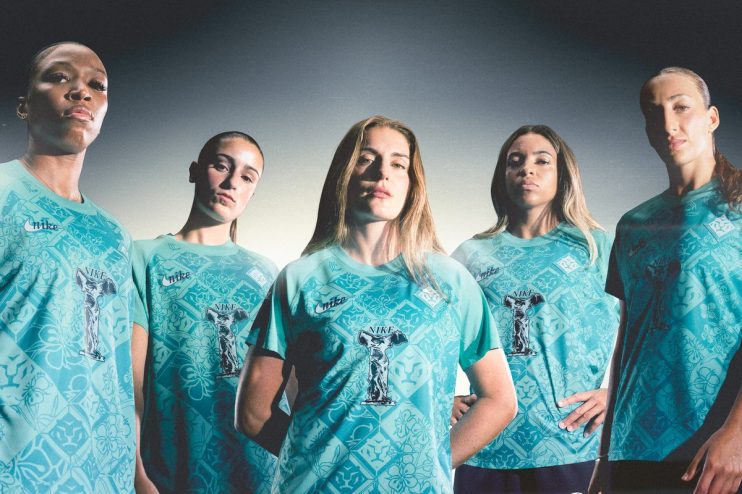 Five female athletes in teal Nike kits with a patterned design and a trophy graphic.