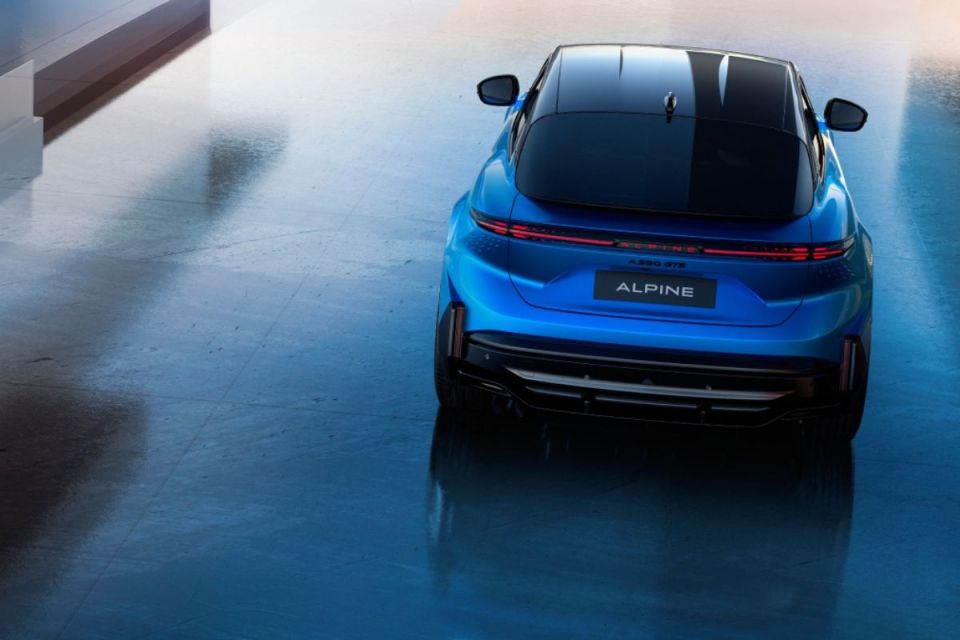 Rear view of a sleek, blue Alpine A290 GTS electric car with black roof, parked on a reflective surface.