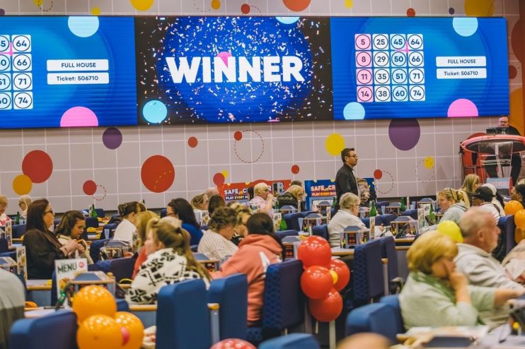 Buzz Bingo hall with players, a large screen displaying WINNER and FULL HOUSE for ticket 506710