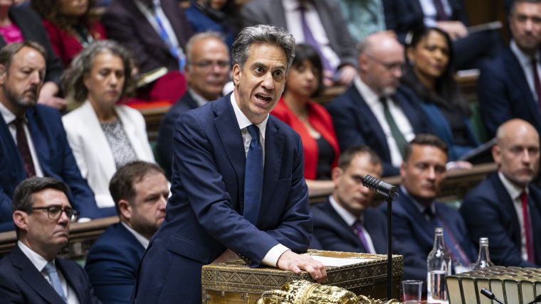 Ed Miliband speaking at dispatch box in the House of Commons, with other Members of Parliament seated behind him.