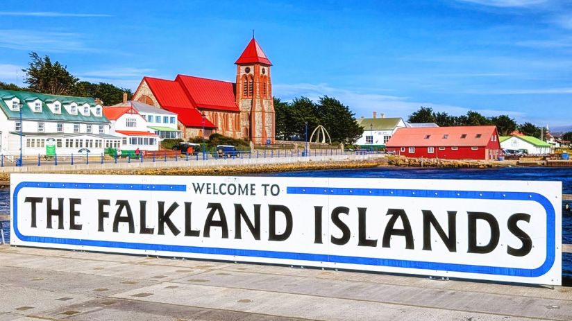 Welcome to the Falkland Islands sign with Stanley harbor and Christ Church Cathedral in background.