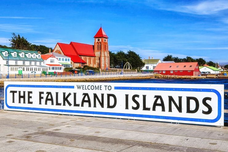 Welcome to the Falkland Islands sign with Stanley harbor and Christ Church Cathedral in background.