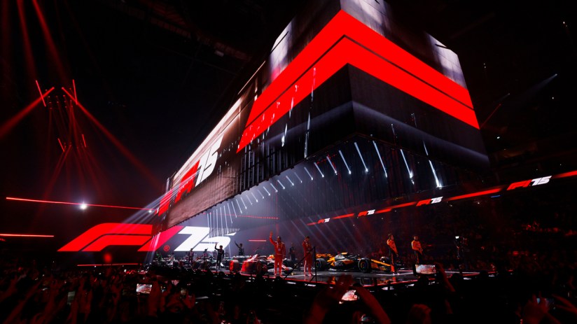 Formula 1 75th anniversary celebration event with F1 cars and drivers on stage, surrounded by red lights and a crowd
