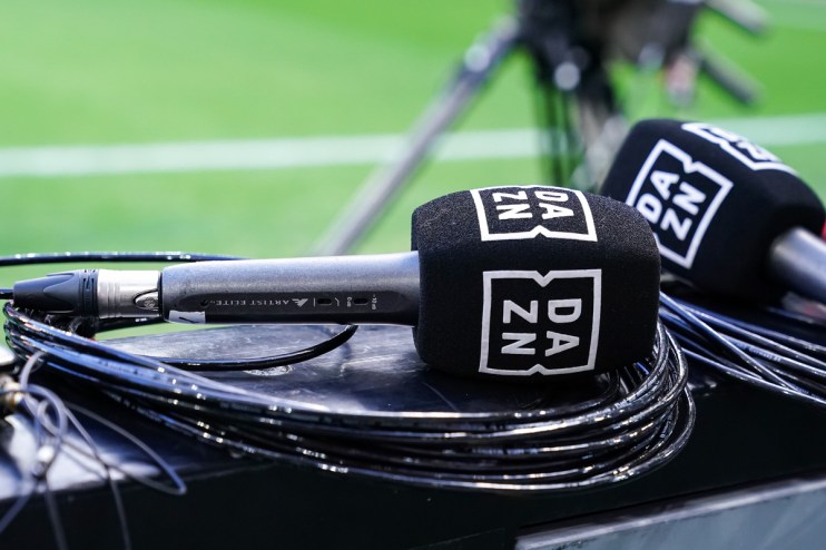 DAZN branded microphones and cables on a surface with a green field in the background