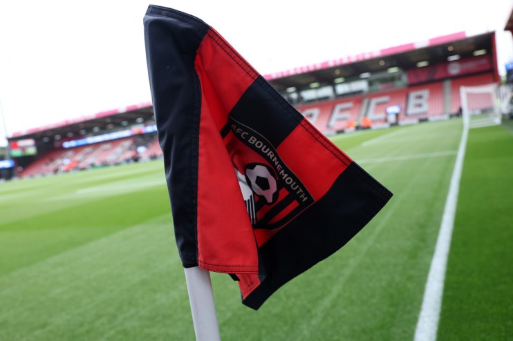 AFC Bournemouth corner flag with team logo, vibrant green pitch, and stadium seating in the background.