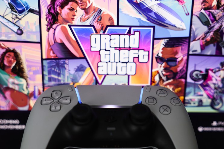 PlayStation 5 controller in front of a screen displaying the Grand Theft Auto logo and game art
