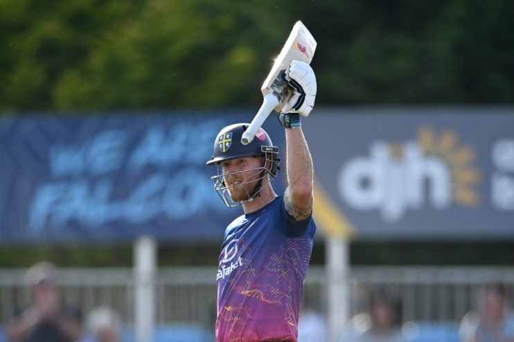 Ben Stokes, in batting gear, raises his cricket bat in celebration on the field.