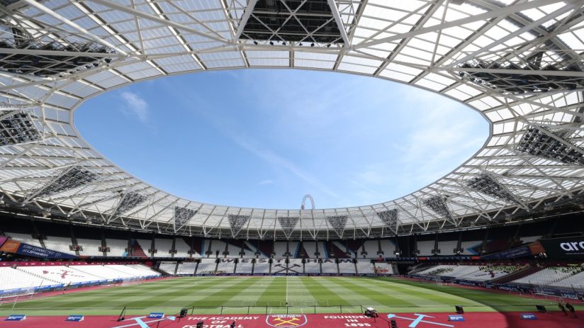 Wide view of an empty London Stadium, home of West Ham United, with a bright blue sky visible through its open roof.