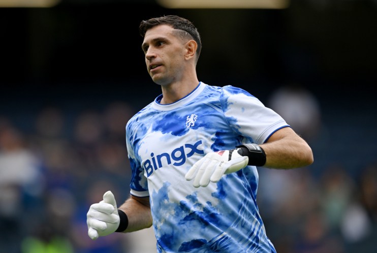 Emiliano Mart&iacute;nez in a blue and white tie-dye Aston Villa goalkeeper kit with BingX sponsor logo and white gloves.