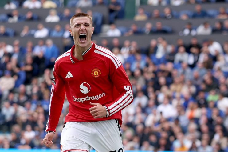 Footballer in Manchester United kit celebrating on the field with a stadium crowd in the background