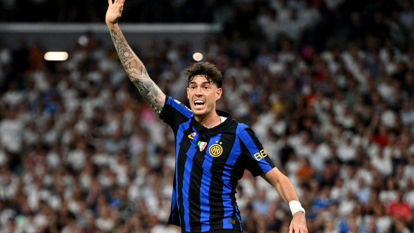 Footballer in a black and blue striped jersey with his arm raised on a crowded field