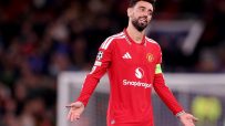 Bruno Fernandes in a red Manchester United jersey, shrugging with open palms on a soccer field
