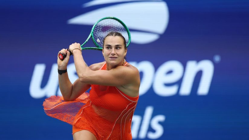 Aryna Sabalenka in an orange tennis dress, mid-swing with a green racket at the US Open.