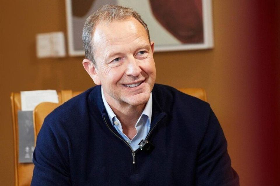 Jason Tarry, CEO of Tesco UK and ROI, smiling during an interview, wearing a navy zip-up top and light blue shirt.