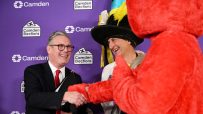 Keir Starmer shaking hands with a man in a tall hat and red furry costume at a Holborn and St Pancras election event.