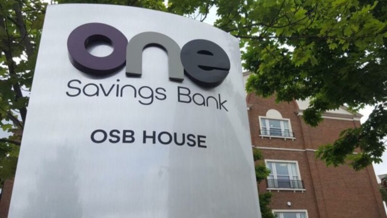 One Savings Bank (OSB) House sign in front of a brick building and green trees.
