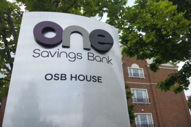 One Savings Bank (OSB) House sign in front of a brick building and green trees.