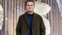 Peter Ruis, CEO, in a dark coat and blue shirt, standing in front of a store window with mannequins