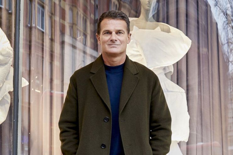 Peter Ruis, CEO, in a dark coat and blue shirt, standing in front of a store window with mannequins
