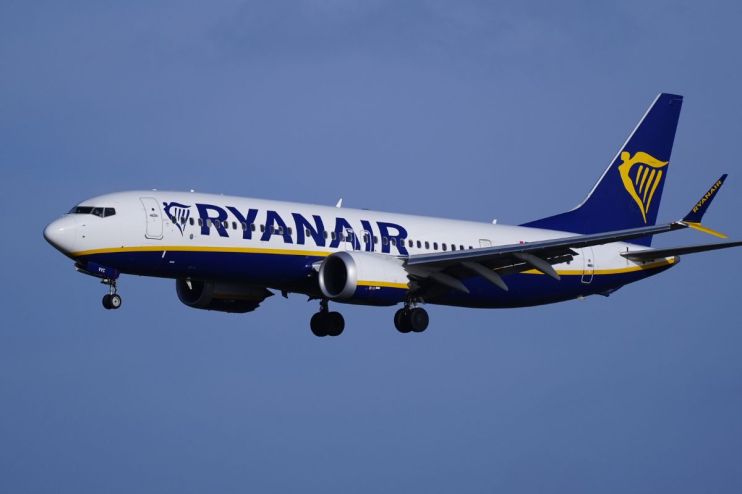 Ryanair Boeing 737 aircraft in flight with landing gear extended against a clear blue sky