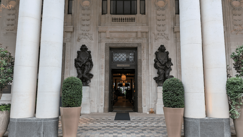 Grand entrance of Six Senses London, featuring large pillars, ornate sculptures, and a WHITELEYS sign above the door.